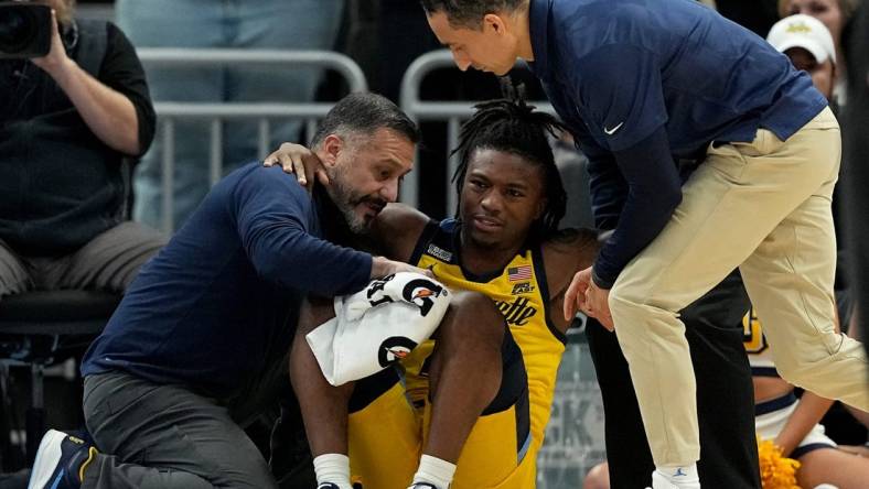 Marquette guard Sean Jones (22) is aided by a member of the training staff and head coach Shaka Smart, right, after being injured during the second half of their game Wednesday, January 10, 2024 at Fiserv Forum in Milwaukee, Wisconsin. Butler beat Marquette 69-62.