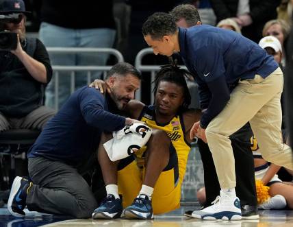 Marquette guard Sean Jones (22) is aided by a member of the training staff and head coach Shaka Smart, right, after being injured during the second half of their game Wednesday, January 10, 2024 at Fiserv Forum in Milwaukee, Wisconsin. Butler beat Marquette 69-62.