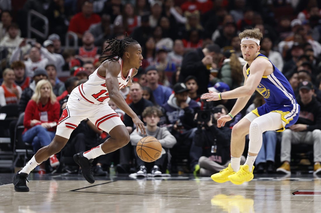 Jan 12, 2024; Chicago, Illinois, USA; Chicago Bulls guard Ayo Dosunmu (12) drives against Golden State Warriors guard Brandin Podziemski (2) during the first half at United Center. Mandatory Credit: Kamil Krzaczynski-USA TODAY Sports