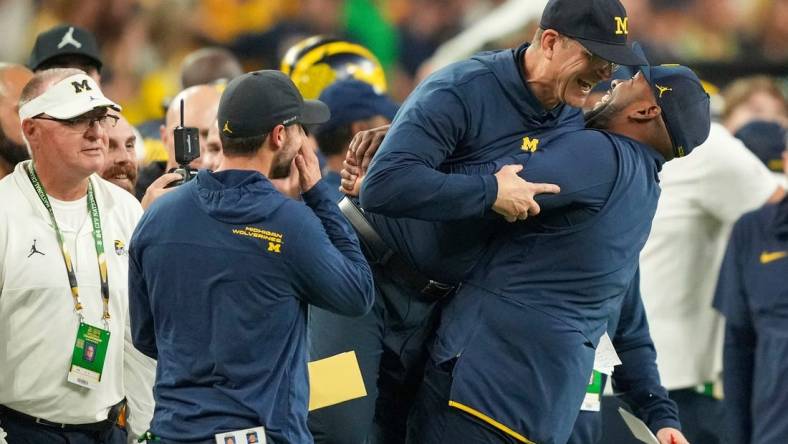 Michigan head coach Jim Harbaugh is lifted off the ground by offensive coordinator Sherrone Moore after Michigan won the College Football Playoff national championship game against Washington at NRG Stadium in Houston on Monday, Jan. 8, 2024.