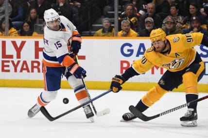 Jan 13, 2024; Nashville, Tennessee, USA; New York Islanders right wing Cal Clutterbuck (15) shoots the puck against Nashville Predators center Ryan O'Reilly (90) during the second period at Bridgestone Arena. Mandatory Credit: Christopher Hanewinckel-USA TODAY Sports