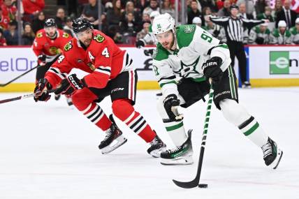 Jan 13, 2024; Chicago, Illinois, USA;  Dallas Stars forward Tyler Seguin (91) controls the puck while being defended by Chicago Blackhawks defenseman Seth Jones (4) in the second period at United Center. Mandatory Credit: Jamie Sabau-USA TODAY Sports