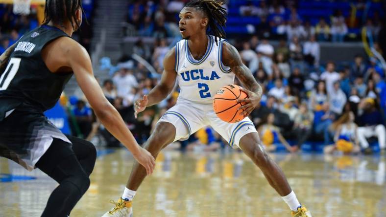 January 14, 2024; Los Angeles, California, USA; UCLA Bruins guard Dylan Andrews (2) controls the ball against Washington Huskies guard Koren Johnson (0) during the second half at Pauley Pavilion. Mandatory Credit: Gary A. Vasquez-USA TODAY Sports