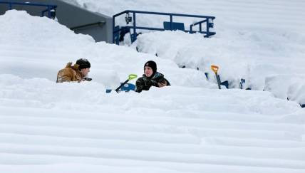 Shovelers take a break from clearing snow inside Highmark Stadium.