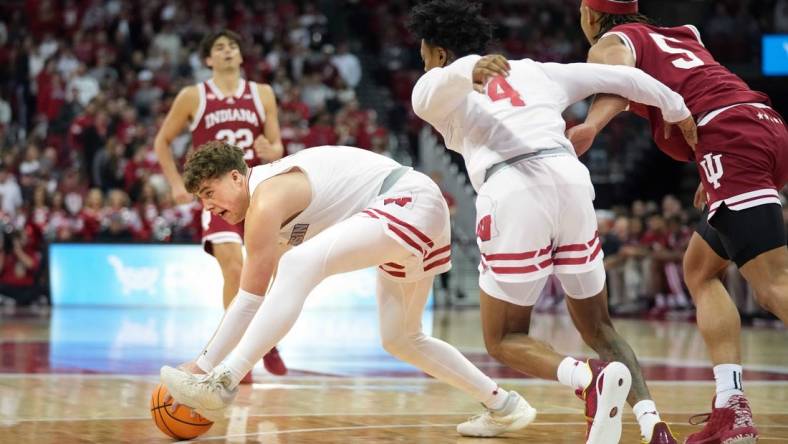 Jan 19, 2024; Madison, Wisconsin, USA; Wisconsin Badgers guard Max Klesmit (11) picks up a loose ball against Indiana Hoosiers forward Malik Reneau (5) and teammate Wisconsin Badgers guard Kamari McGee (4) during the first half at the Kohl Center. Mandatory Credit: Kayla Wolf-USA TODAY Sports