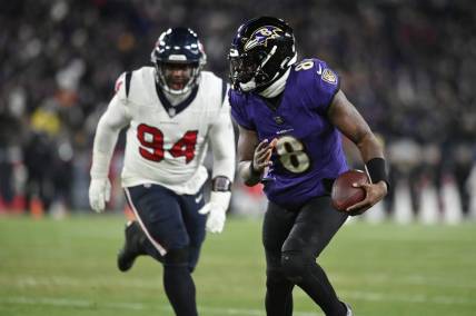 Jan 20, 2024; Baltimore, MD, USA; Baltimore Ravens quarterback Lamar Jackson (8) runs the ball to score a touchdown against Houston Texans defensive tackle Khalil Davis (94) during the fourth quarter of a 2024 AFC divisional round game at M&T Bank Stadium. Mandatory Credit: Tommy Gilligan-USA TODAY Sports