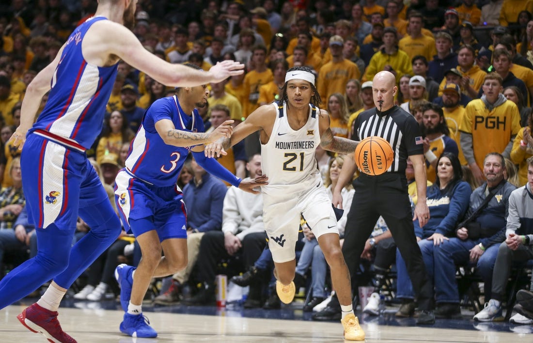 Jan 20, 2024; Morgantown, West Virginia, USA; West Virginia Mountaineers guard RaeQuan Battle (21) dribbles the ball past Kansas Jayhawks guard Dajuan Harris Jr. (3) during the second half at WVU Coliseum. Mandatory Credit: Ben Queen-USA TODAY Sports