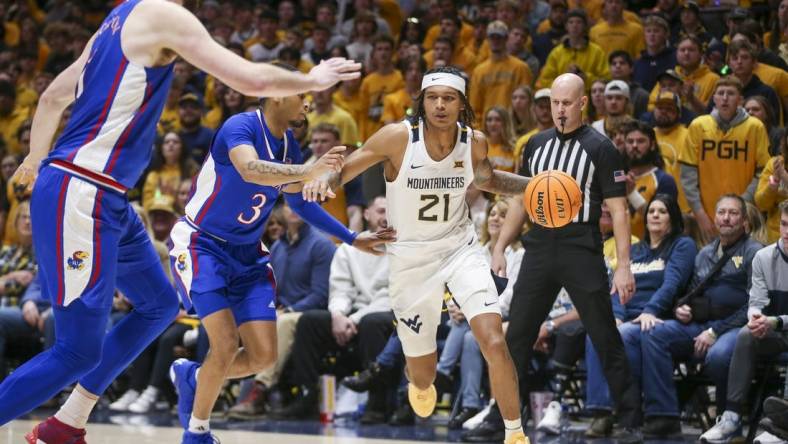 Jan 20, 2024; Morgantown, West Virginia, USA; West Virginia Mountaineers guard RaeQuan Battle (21) dribbles the ball past Kansas Jayhawks guard Dajuan Harris Jr. (3) during the second half at WVU Coliseum. Mandatory Credit: Ben Queen-USA TODAY Sports