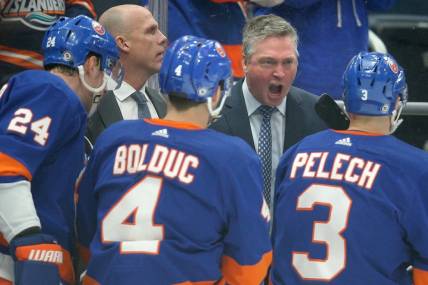Jan 21, 2024; Elmont, New York, USA; New York Islanders head coach Patrick Roy talks to defensemen Scott Mayfield (24) and Samuel Bolduc (4) and Adam Pelech (3) during the first period against the Dallas Stars at UBS Arena. Mandatory Credit: Brad Penner-USA TODAY Sports