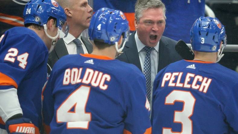 Jan 21, 2024; Elmont, New York, USA; New York Islanders head coach Patrick Roy talks to defensemen Scott Mayfield (24) and Samuel Bolduc (4) and Adam Pelech (3) during the first period against the Dallas Stars at UBS Arena. Mandatory Credit: Brad Penner-USA TODAY Sports