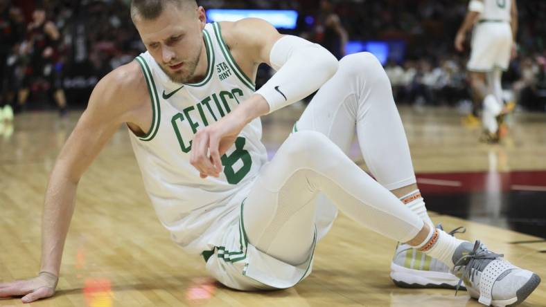 Jan 25, 2024; Miami, Florida, USA; Boston Celtics center Kristaps Porzingis (8) reacts on the floor after a play against the Miami Heat during the third quarter at Kaseya Center. Mandatory Credit: Sam Navarro-USA TODAY Sports