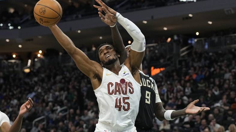 Jan 26, 2024; Milwaukee, Wisconsin, USA;  Cleveland Cavaliers guard Donovan Mitchell (45) reaches for a rebound in front of Milwaukee Bucks forward Bobby Portis (9) during the second quarter at Fiserv Forum. Mandatory Credit: Jeff Hanisch-USA TODAY Sports