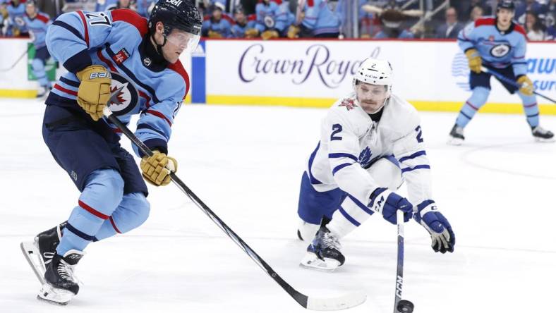 Jan 27, 2024; Winnipeg, Manitoba, CAN; Winnipeg Jets left wing Nikolaj Ehlers (27) is stick checked by Toronto Maple Leafs defenseman Simon Benoit (2) in the second period at Canada Life Centre. Mandatory Credit: James Carey Lauder-USA TODAY Sports