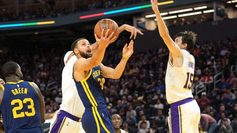 Jan 27, 2024; San Francisco, California, USA; Golden State Warriors guard Stephen Curry (center) shoots against Los Angeles Lakers forward Anthony Davis (obscured) and guard Austin Reaves (15) during the third quarter at Chase Center. Mandatory Credit: Darren Yamashita-USA TODAY Sports