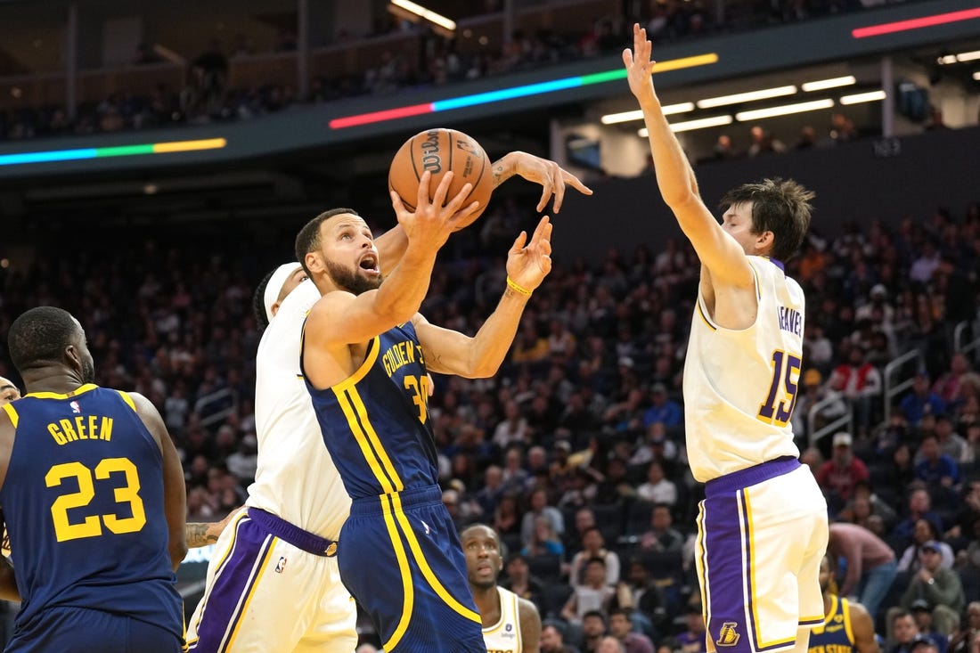 Jan 27, 2024; San Francisco, California, USA; Golden State Warriors guard Stephen Curry (center) shoots against Los Angeles Lakers forward Anthony Davis (obscured) and guard Austin Reaves (15) during the third quarter at Chase Center. Mandatory Credit: Darren Yamashita-USA TODAY Sports
