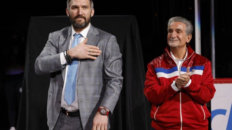 Apr 26, 2022; Washington, District of Columbia, USA; Injured Washington Capitals left wing Alex Ovechkin (L) gestures to fans while standing next to Capitals owner Ted Leonsis (R) during a ceremony honoring his becoming 3rd highest goal scorer in NHL history prior to the Capitals game against the New York Islanders at Capital One Arena. Mandatory Credit: Geoff Burke-USA TODAY Sports