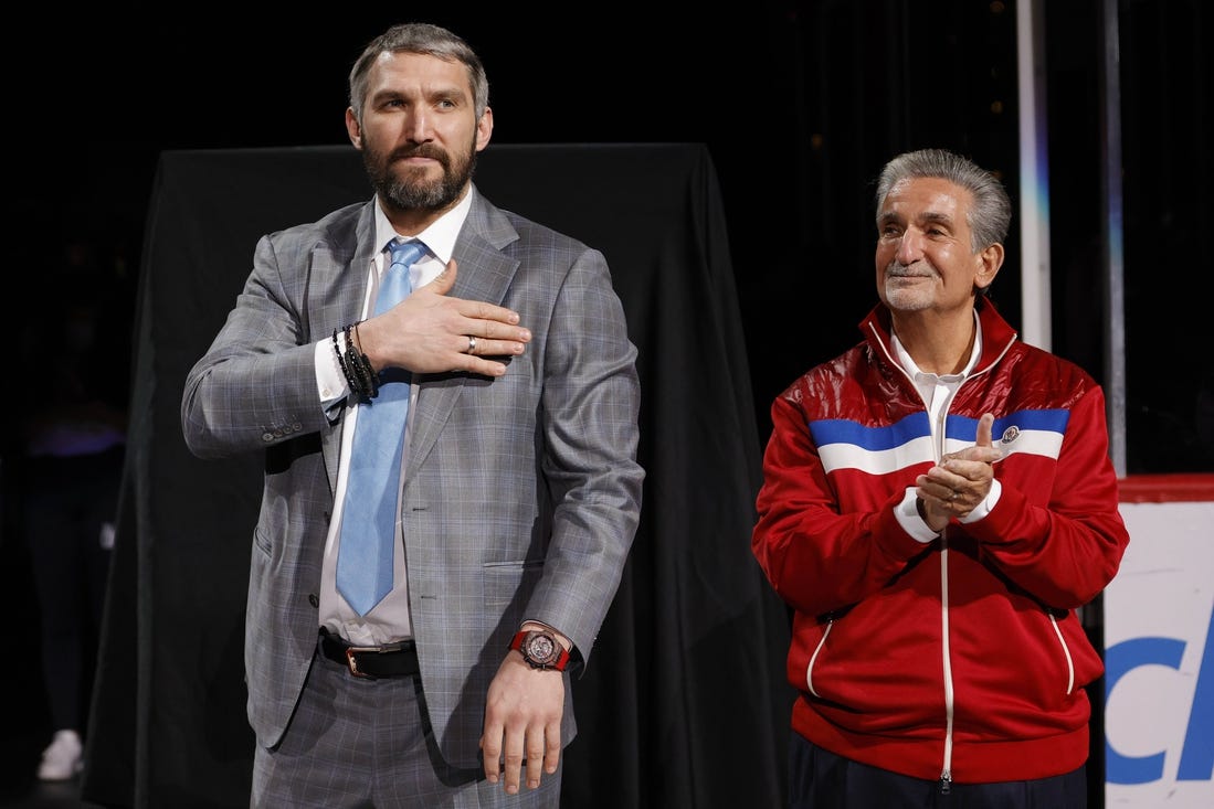 Apr 26, 2022; Washington, District of Columbia, USA; Injured Washington Capitals left wing Alex Ovechkin (L) gestures to fans while standing next to Capitals owner Ted Leonsis (R) during a ceremony honoring his becoming 3rd highest goal scorer in NHL history prior to the Capitals game against the New York Islanders at Capital One Arena. Mandatory Credit: Geoff Burke-USA TODAY Sports