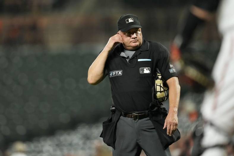 Sep 6, 2022; Baltimore, Maryland, USA; Umpire Jeff Nelson listens for the results of an instant replay review of Toronto Blue Jays shortstop Bo Bichette's (not pictured) hit against the Baltimore Orioles during the third inning at Oriole Park at Camden Yards. The review determined that Bichette hit a home run. Mandatory Credit: Brent Skeen-USA TODAY Sports