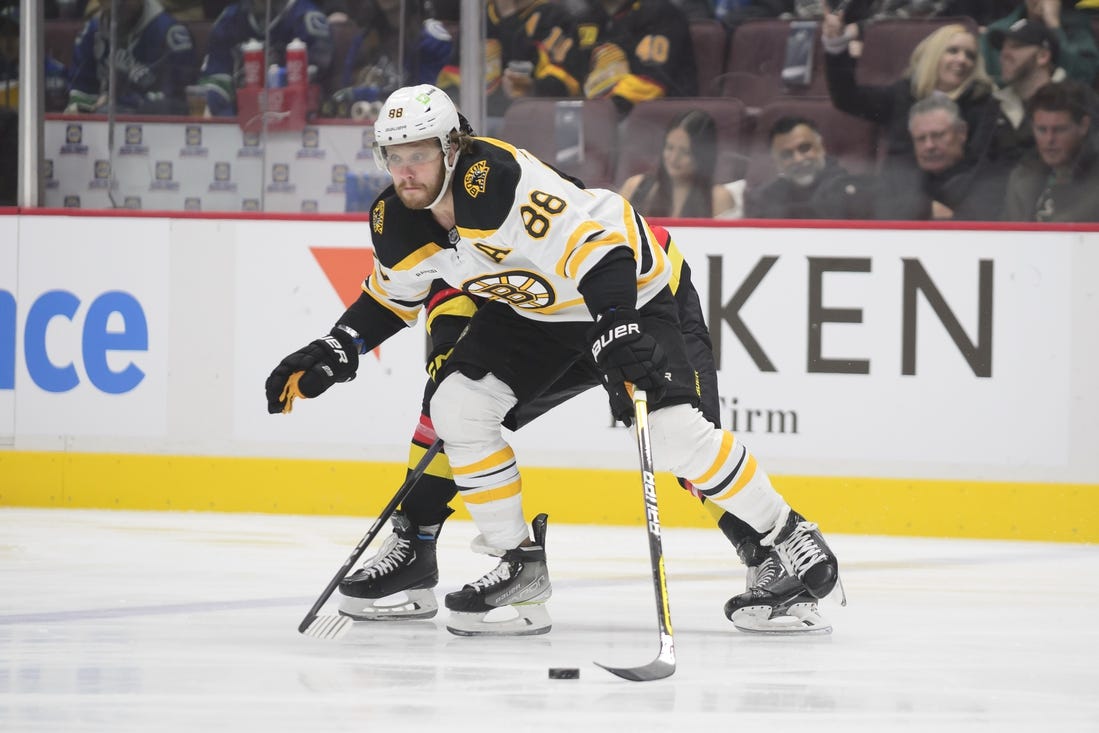 Feb 25, 2023; Vancouver, British Columbia, CAN;  Boston Bruins forward David Pastrnak  (88) reaches for the puck against the Vancouver Canucks during the first period at Rogers Arena. Mandatory Credit: Anne-Marie Sorvin-USA TODAY Sports