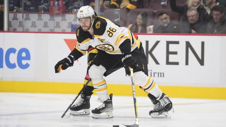 Feb 25, 2023; Vancouver, British Columbia, CAN;  Boston Bruins forward David Pastrnak  (88) reaches for the puck against the Vancouver Canucks during the first period at Rogers Arena. Mandatory Credit: Anne-Marie Sorvin-USA TODAY Sports