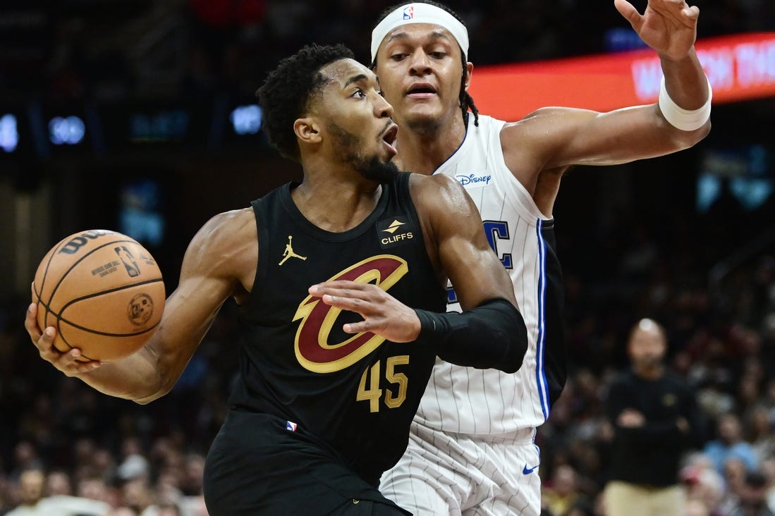 Dec 6, 2023; Cleveland, Ohio, USA; Cleveland Cavaliers guard Donovan Mitchell (45) drives to the basket against Orlando Magic forward Paolo Banchero (5) during the second half at Rocket Mortgage FieldHouse. Mandatory Credit: Ken Blaze-USA TODAY Sports