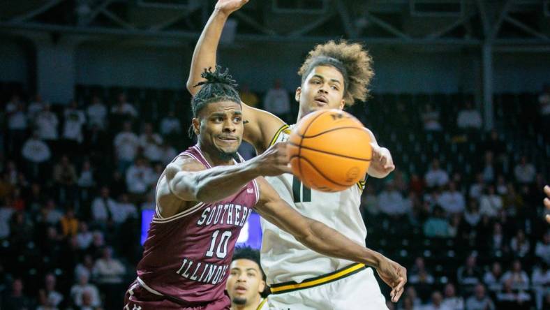 Dec 16, 2023; Wichita, Kansas, USA; Southern Illinois Salukis Xavier Johnson (10) passes around Wichita State Shockers forward Kenny Pohto (11) during the second half at Charles Koch Arena. Mandatory Credit: William Purnell-USA TODAY Sports