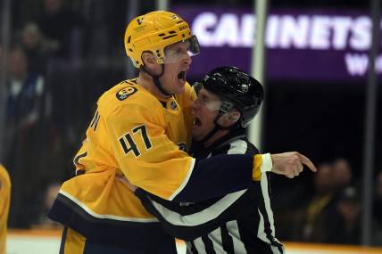 Dec 19, 2023; Nashville, Tennessee, USA; Nashville Predators right wing Michael McCarron (47) is held back by linesman Libor Suchanek (60) before receiving a game misconduct during the first period against the Vancouver Canucks at Bridgestone Arena. Mandatory Credit: Christopher Hanewinckel-USA TODAY Sports