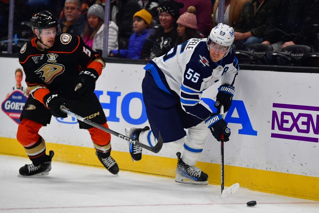 Jan 5, 2024; Anaheim, California, USA; Winnipeg Jets center Mark Scheifele (55) moves the puck ahead of Anaheim Ducks defenseman Urho Vaakanainen (5) during the first period at Honda Center. Mandatory Credit: Gary A. Vasquez-USA TODAY Sports