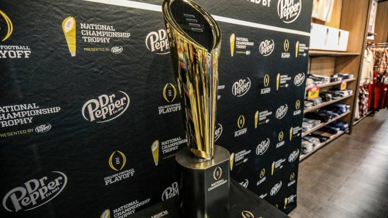 Fans stop to take photos with the College Football National Championship trophy at Meijer in Ypsilanti, Mich. on Thursday, Jan. 11, 2024. The trophy is going on a tour for fans to see presented by Dr. Pepper.