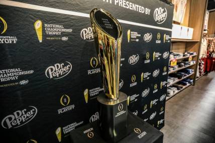 Fans stop to take photos with the College Football National Championship trophy at Meijer in Ypsilanti, Mich. on Thursday, Jan. 11, 2024. The trophy is going on a tour for fans to see presented by Dr. Pepper.