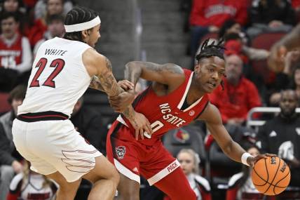 Jan 13, 2024; Louisville, Kentucky, USA;  North Carolina State Wolfpack guard DJ Horne (0) drives against Louisville Cardinals guard Tre White (22) during the first half at KFC Yum! Center. Mandatory Credit: Jamie Rhodes-USA TODAY Sports