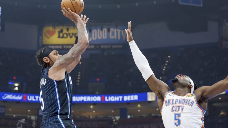 Jan 13, 2024; Oklahoma City, Oklahoma, USA; Orlando Magic forward Paolo Banchero (5) shoots as Oklahoma City Thunder guard Luguentz Dort (5) defends during the first quarter at Paycom Center. Mandatory Credit: Alonzo Adams-USA TODAY Sports