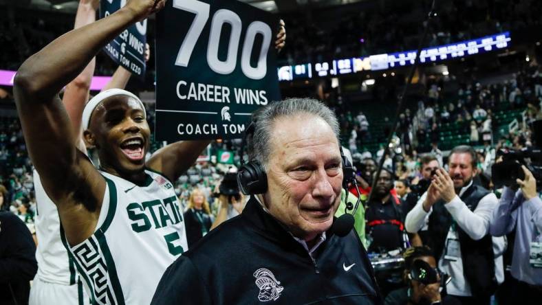 Michigan State guard Tre Holloman (5) holds a sign celebrating 700 career wins as head coach Tom Izzo is being interviewed after MSU's 81-62 win over Michigan at Breslin Center in East Lansing on Tuesday, Jan. 30, 2024.