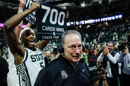 Michigan State guard Tre Holloman (5) holds a sign celebrating 700 career wins as head coach Tom Izzo is being interviewed after MSU's 81-62 win over Michigan at Breslin Center in East Lansing on Tuesday, Jan. 30, 2024.