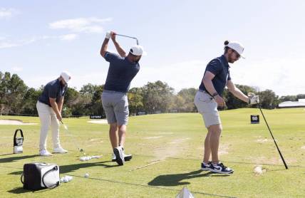 Feb 2, 2024; Playa del Carmen, Quintana Roo, MEX; Jon Rahm of Team Legion XIII, center, hits on the practice range with teammates Tyrrell Hatton, left, and Kieran Vincent before the first round of the LIV Golf Mayakoba tournament at El Chamaleon Golf Course. Mandatory Credit: Erich Schlegel-USA TODAY Sports