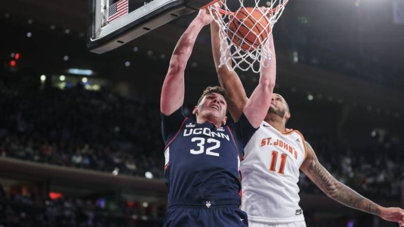 Feb 3, 2024; New York, New York, USA;  Connecticut Huskies center Donovan Clingan (32) dunks past St. John's Red Storm center Joel Soriano (11) in the first half at Madison Square Garden. Mandatory Credit: Wendell Cruz-USA TODAY Sports