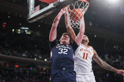 Feb 3, 2024; New York, New York, USA;  Connecticut Huskies center Donovan Clingan (32) dunks past St. John's Red Storm center Joel Soriano (11) in the first half at Madison Square Garden. Mandatory Credit: Wendell Cruz-USA TODAY Sports