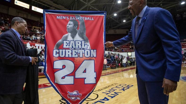 Detroit Mercy athletic director Robert C. Vowels, Jr., left, and Earl Cureton, unveil the No. 24 jersey retirement during the ceremony at Calihan Hall in Detroit, Thursday, Jan. 23, 2020.