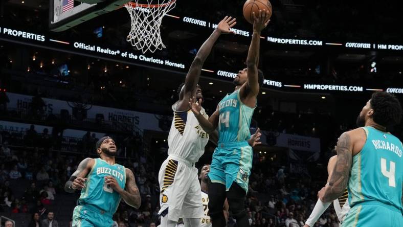 Feb 4, 2024; Charlotte, North Carolina, USA; Charlotte Hornets guard Ish Smith (14) gets a fast break basket defended by Indiana Pacers forward Aaron Nesmith (23) during the first quarter at Spectrum Center. Mandatory Credit: Jim Dedmon-USA TODAY Sports