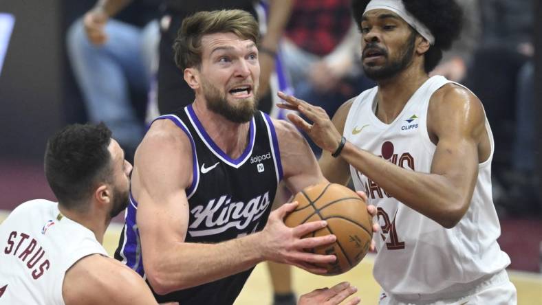 Feb 5, 2024; Cleveland, Ohio, USA; Sacramento Kings forward Domantas Sabonis (10) drives between Cleveland Cavaliers guard Max Strus (1) and center Jarrett Allen (31) in the first quarter at Rocket Mortgage FieldHouse. Mandatory Credit: David Richard-USA TODAY Sports