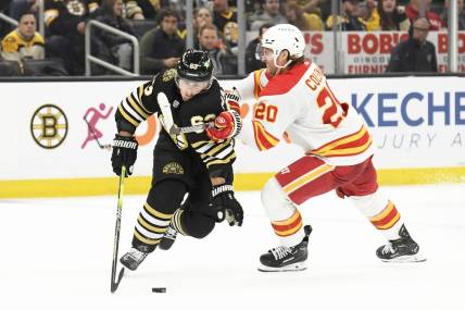 Feb 6, 2024; Boston, Massachusetts, USA; Boston Bruins left wing Brad Marchand (63) controls the puck from Calgary Flames center Blake Coleman (20) during the second period at TD Garden. Mandatory Credit: Bob DeChiara-USA TODAY Sports