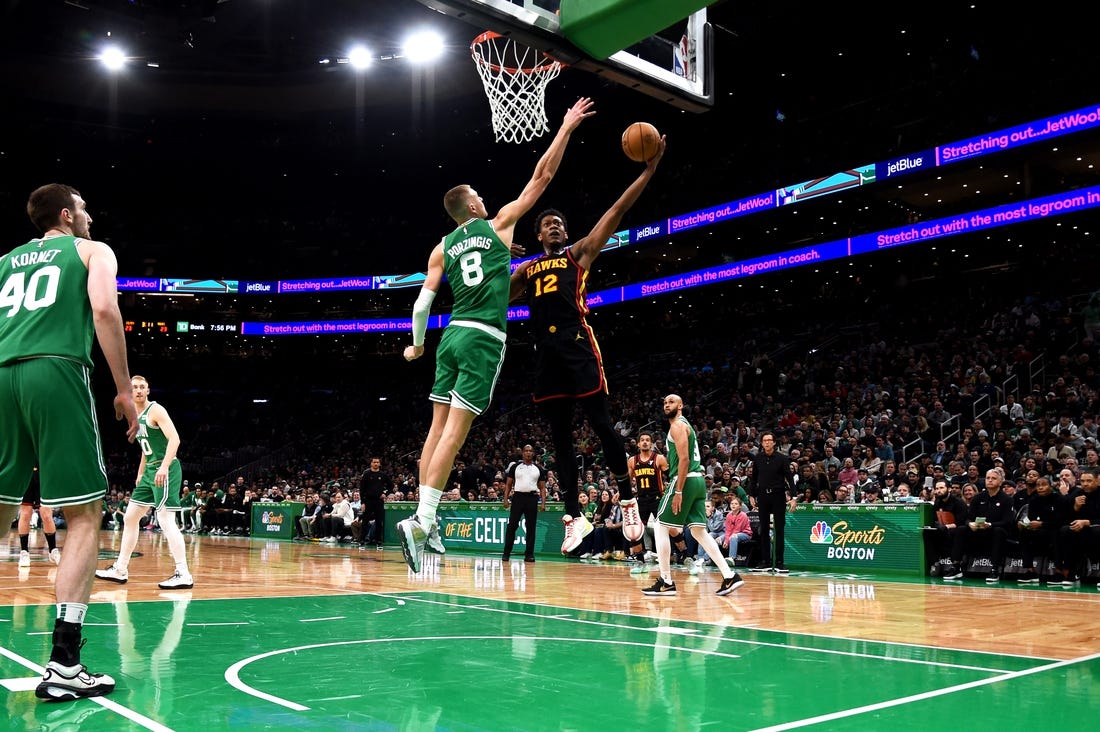 Feb 7, 2024; Boston, Massachusetts, USA;  Atlanta Hawks forward De'Andre Hunter (12) drives to the basket and gets fouled by Boston Celtics center Kristaps Porzingis (8) during the first half at TD Garden. Mandatory Credit: Bob DeChiara-USA TODAY Sports