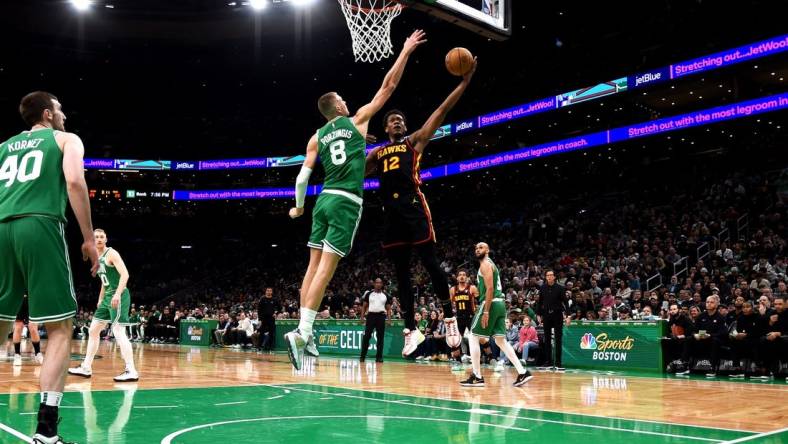 Feb 7, 2024; Boston, Massachusetts, USA;  Atlanta Hawks forward De'Andre Hunter (12) drives to the basket and gets fouled by Boston Celtics center Kristaps Porzingis (8) during the first half at TD Garden. Mandatory Credit: Bob DeChiara-USA TODAY Sports