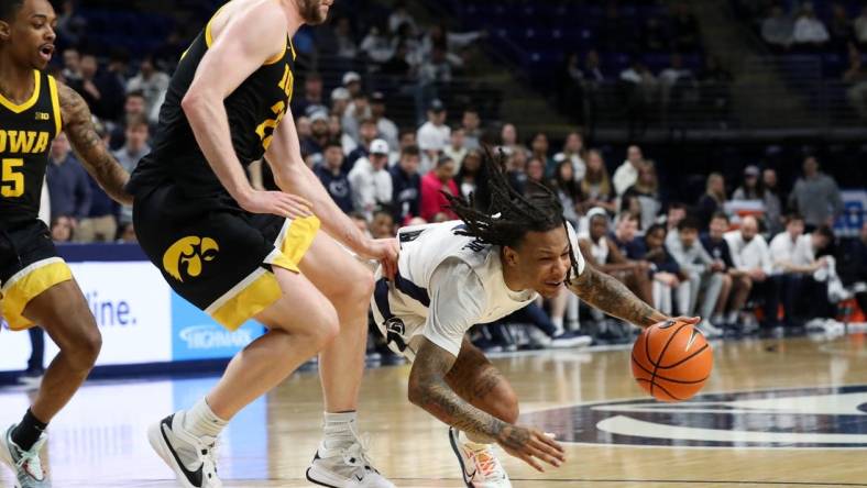 Feb 8, 2024; University Park, Pennsylvania, USA; Penn State Nittany Lions guard Ace Baldwin Jr (1) looses his footing while dribbling the ball around Iowa Hawkeyes forward Ben Krikke (23) during the first half at Bryce Jordan Center. Mandatory Credit: Matthew O'Haren-USA TODAY Sports