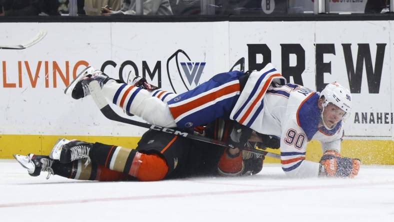 Feb 9, 2024; Anaheim, California, USA; Edmonton Oilers right wing Corey Perry (90) falls on top of an Anaheim Ducks player during the first period of a game at Honda Center. Mandatory Credit: Jessica Alcheh-USA TODAY Sports