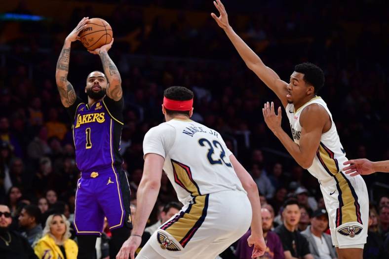 Feb 9, 2024; Los Angeles, California, USA; Los Angeles Lakers guard D'Angelo Russell (1) shoots against New Orleans Pelicans guard CJ McCollum (3) and forward Larry Nance Jr. (22) during the first half at Crypto.com Arena. Mandatory Credit: Gary A. Vasquez-USA TODAY Sports
