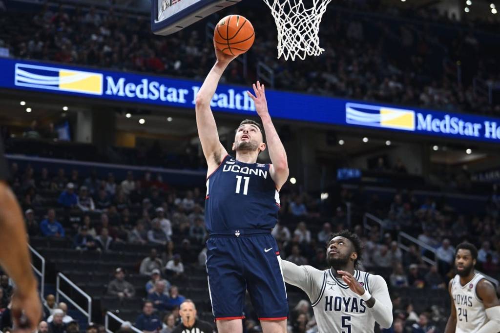 Feb 10, 2024; Washington, District of Columbia, USA; Connecticut Huskies forward Alex Karaban (11) shoots as Georgetown Hoyas guard Jay Heath (5) looks on during the first half at Capital One Arena. Mandatory Credit: Brad Mills-USA TODAY Sports