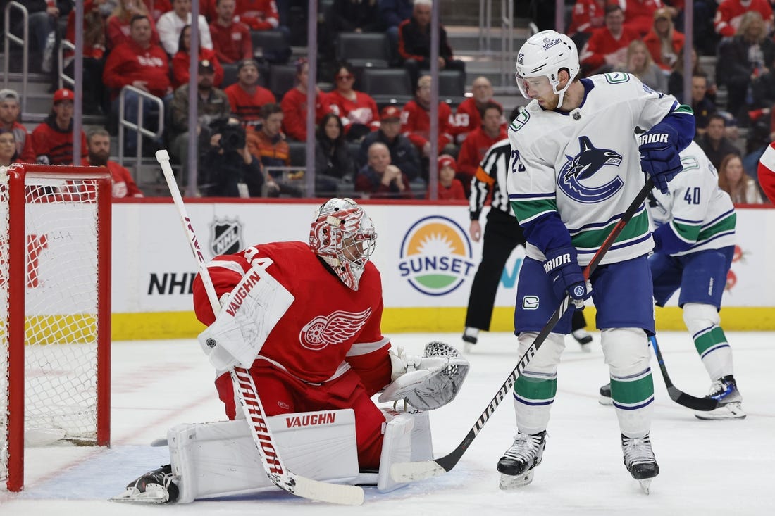 Feb 10, 2024; Detroit, Michigan, USA;  Detroit Red Wings goaltender Alex Lyon (34) makes a save in front of Vancouver Canucks center Elias Lindholm (23) in the first period at Little Caesars Arena. Mandatory Credit: Rick Osentoski-USA TODAY Sports