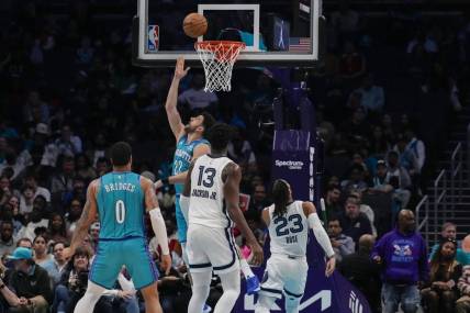 Feb 10, 2024; Charlotte, North Carolina, USA; Charlotte Hornets guard Vasilije Micic (22) with a reverse layup defended by Memphis Grizzlies guard Derrick Rose (23) during the second half at Spectrum Center. Mandatory Credit: Jim Dedmon-USA TODAY Sports