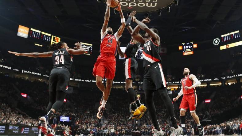 Feb 10, 2024; Portland, Oregon, USA; New Orleans Pelicans small forward Brandon Ingram (14) drives for the basket between Portland Trail Blazers forward Jabari Walker (34) and small forward Jerami Grant (9, right) during the first half at Moda Center. Mandatory Credit: Soobum Im-USA TODAY Sports